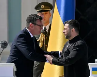 Andy Burnham shakes hands with Volodymyr Zelensky before a Ukrainian flag at a ceremony