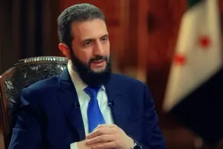 A man in a suit sits in a chair