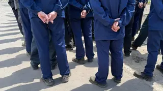 一排身穿深藍色制服的男子背對鏡頭站立，雙手在背後互握。