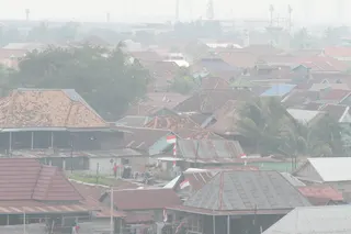 A man stands among houses as haze from wildfires blankets the city of Palembang, South Sumatra, Indonesia, on Tuesday. Photo: AP