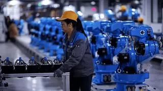 成都一家工廠裡，一名女攻正在搬動機器。