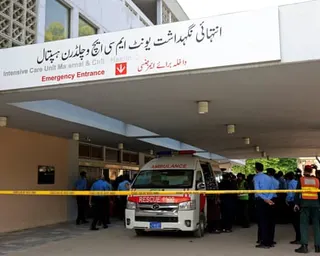 Police officers gather near an ambulance outside a hospital's emergency entrance