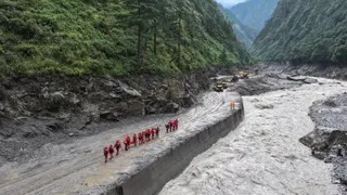 中国消防救援人员周五在西藏自治区吉隆县一段在泥石流灾害中受损的道路上，展开搜救行动。（图取自法新社）