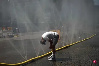 德国6月底多地气温超过40摄氏度，单在一周内就有约9600人死于与高温相关原因。图为一名男子6月25日在德国西部科隆，利用设在街道的喷水管降温。 （法新社）
