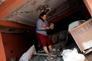 一名妇女重返尼泊尔特里舒利灾区，在满是泥沙的房屋里找回一个储蓄罐。（路透社）