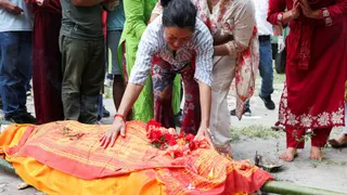 Muna Khadka mourns next to her son's body before his cremation inside the cremation ground, in Chitwan, Nepal.