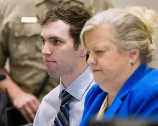 a man sits in court next to his lawyer