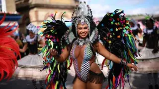 Woman in colourful outfit with colourful feathers dances