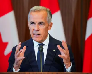 Mark Carney speaking in front of Canadian flags