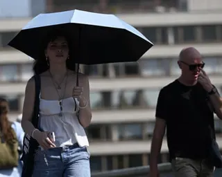 A woman in London shades herself with an umbrella