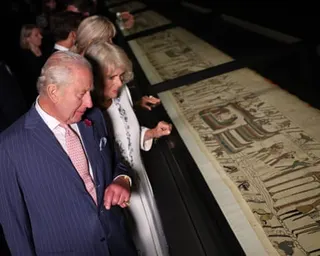 King Charles III and Queen Camilla examine the Bayeux Tapestry displayed under glass
