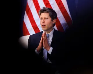 a man speaking in front of an American flag