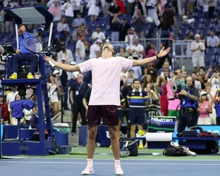 Alexander Zverev raises his arms and looks skyward, celebrating his narrow US Open win.