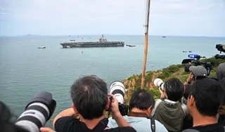 Waiting journalists take photos of the USS Abraham Lincoln aircraft carrier off Laem Chabang port, near the city of Pattaya in Thailand after more than 270 days at sea.