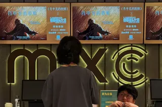 一個女子站在電影院售票窗口前，牆上掛著《肖申克的救贖》海報