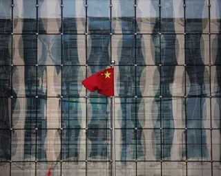 A Chinese national flag flutters at the headquarters of a commercial bank on a financial street near the headquarters of the People's Bank of China in central Beijing