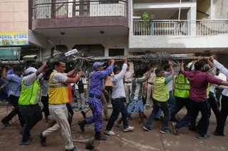 Rescue workers carry an electric pole near the site of a collapsed building in New Delhi on Sunday. Photo: AP