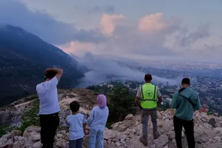 People watch a smoke rise from an Israeli air strike that hit a house in Arab Salim village, southern Lebanon
