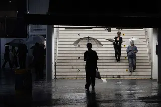 Commuters exit a train station during a heavy rainstorm in Tokyo on Sunday. Photo: AFP